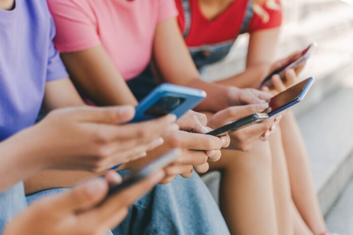 Closeup,,Group,Of,Teenagers,Holding,Mobile,Phones,Watching,Video,,Communication