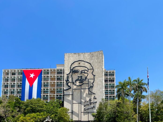 Che,Guevara,Mural,And,A,Cuban,Flag,On,A,Government